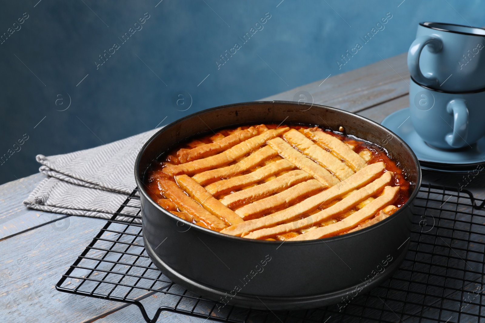 Photo of Delicious apricot pie in baking dish and cups on grey wooden table