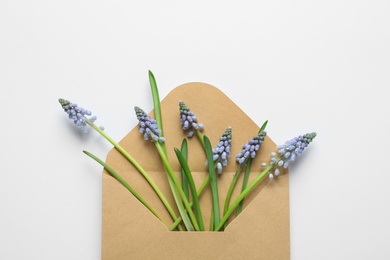 Photo of Envelope with beautiful spring muscari flowers on light background, top view