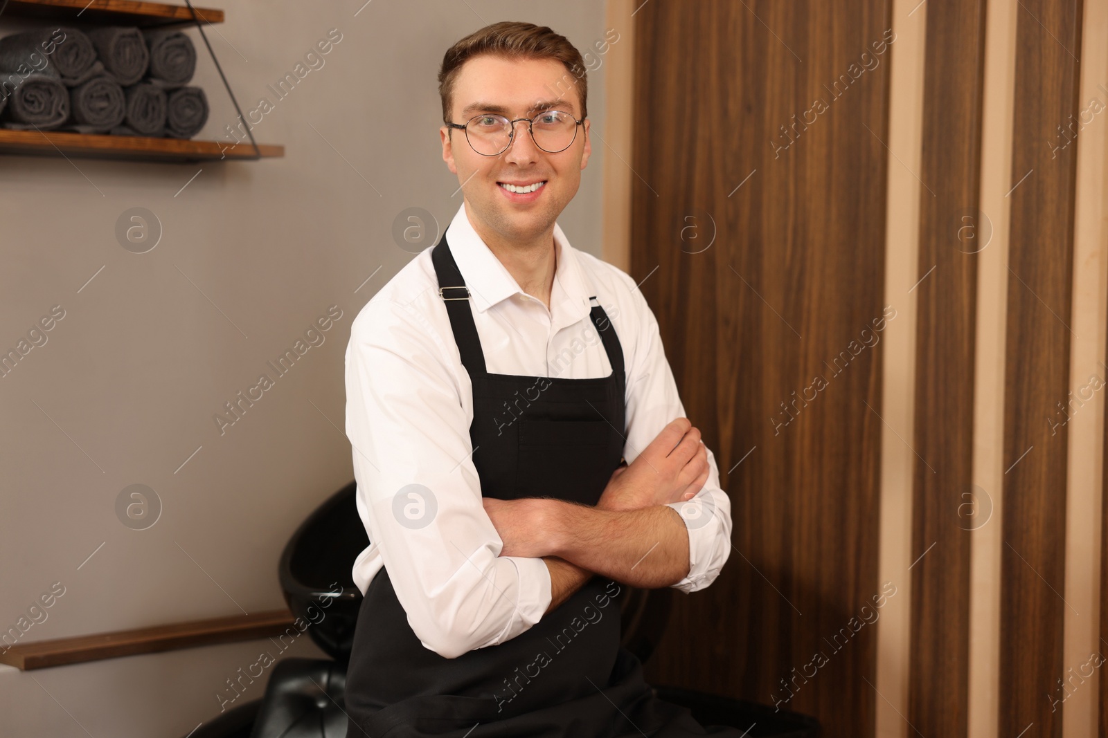 Photo of Portrait of professional hairdresser wearing apron in beauty salon