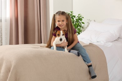 Photo of Cute girl hugging her dog on bed at home. Adorable pet