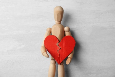 Photo of Wooden puppet with torn cardboard heart on gray background, top view. Relationship problems