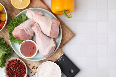 Photo of Flat lay composition with marinade and raw chicken drumsticks on white tiled table. Space for text