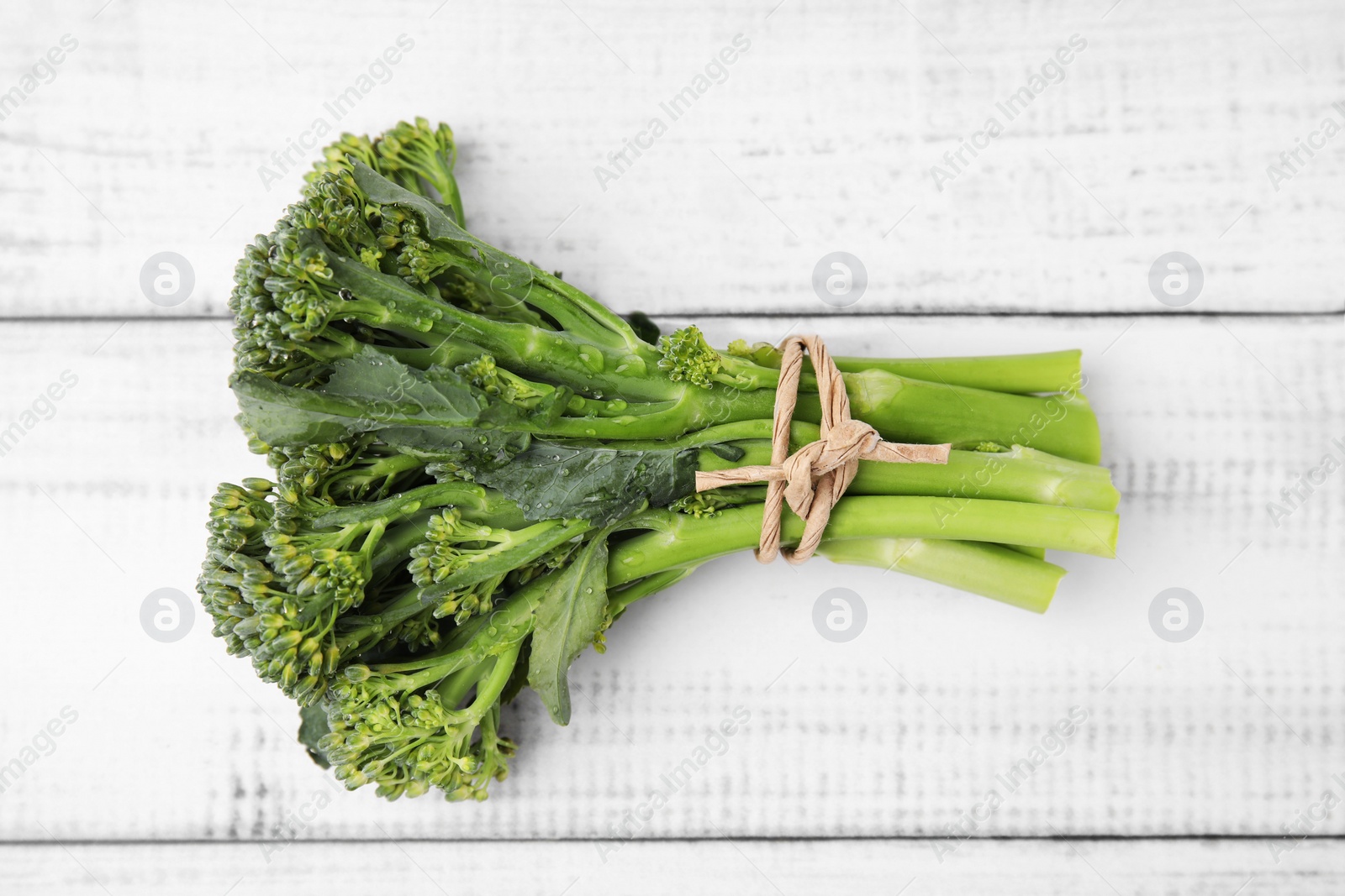 Photo of Fresh raw broccolini on white wooden table, top view. Healthy food