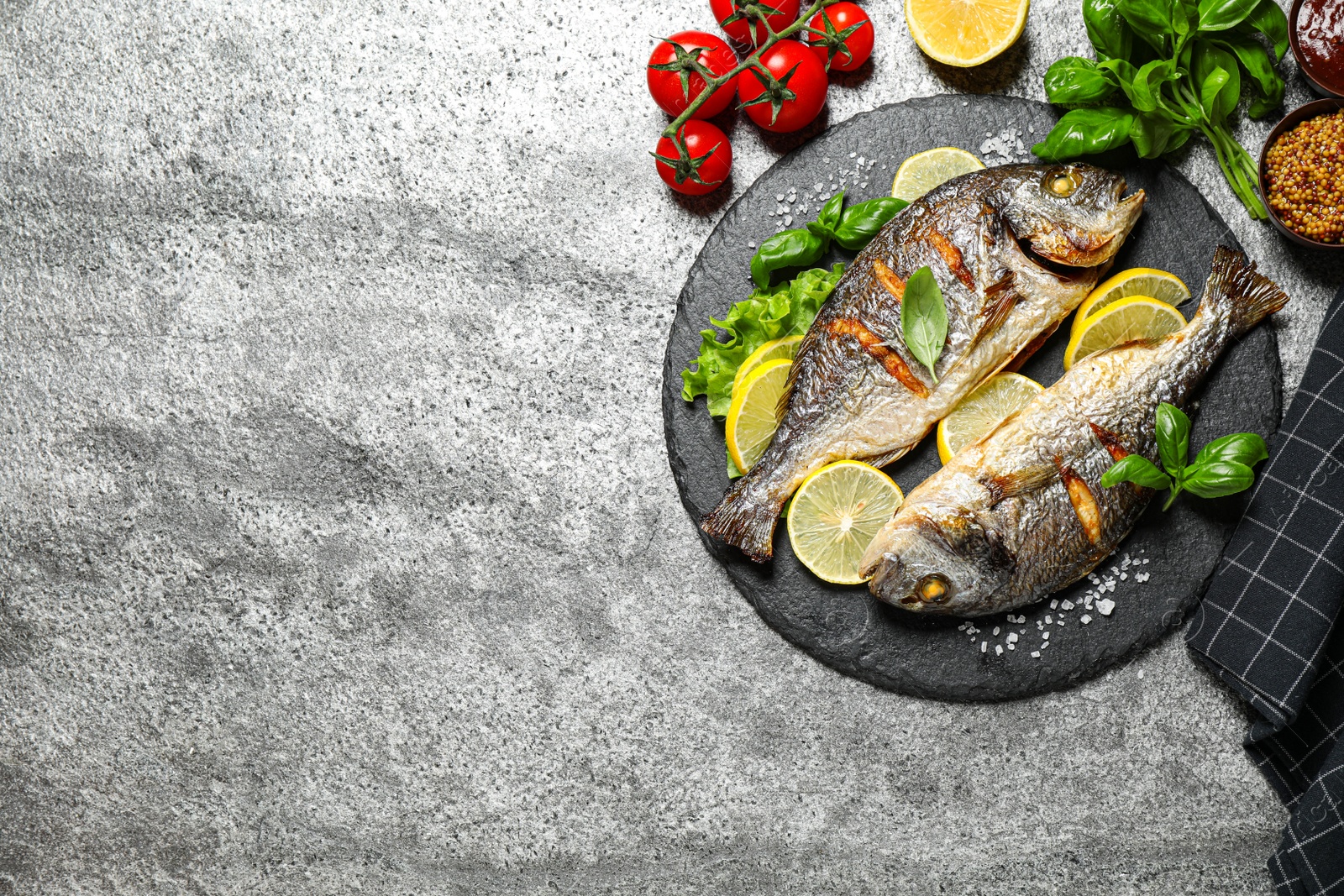 Photo of Delicious roasted fish with lemon on grey table, flat lay. Space for text