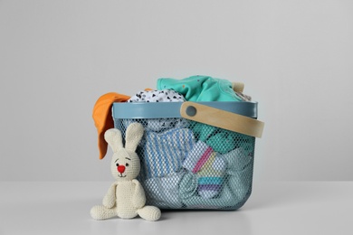 Photo of Laundry basket with different children's clothes and toy on light background