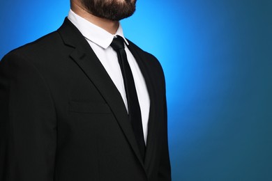 Photo of Businessman in suit and necktie on blue background, closeup. Space for text