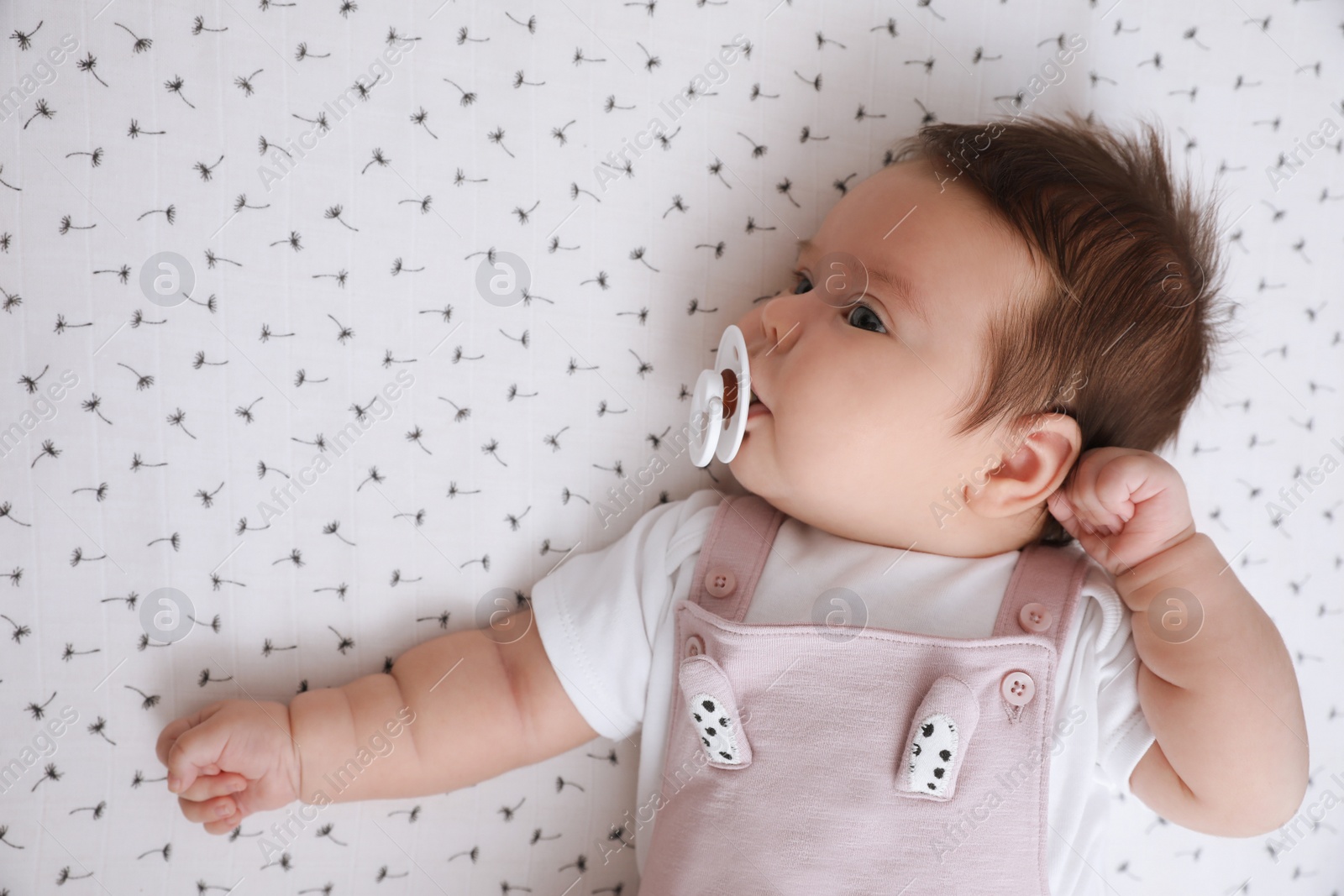 Photo of Cute little baby with pacifier lying on blanket, top view. Bedtime