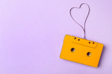 Photo of Top view of music cassette and heart made with tape on violet background, space for text. Listening love song