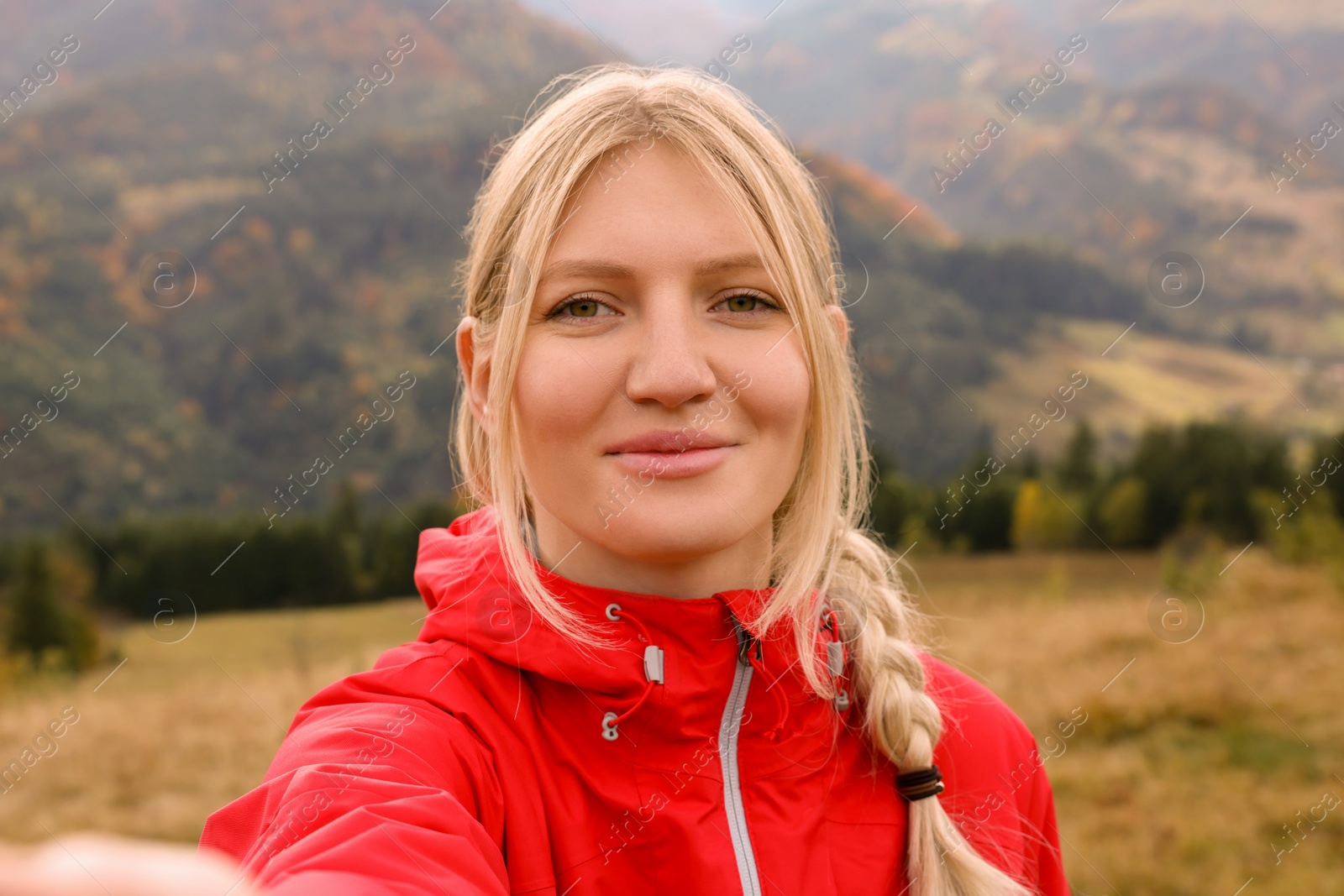 Photo of Happy young woman taking selfie in mountains
