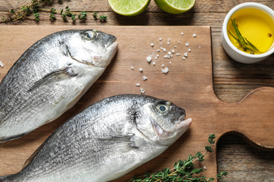 Photo of Raw dorada fish on wooden table, flat lay