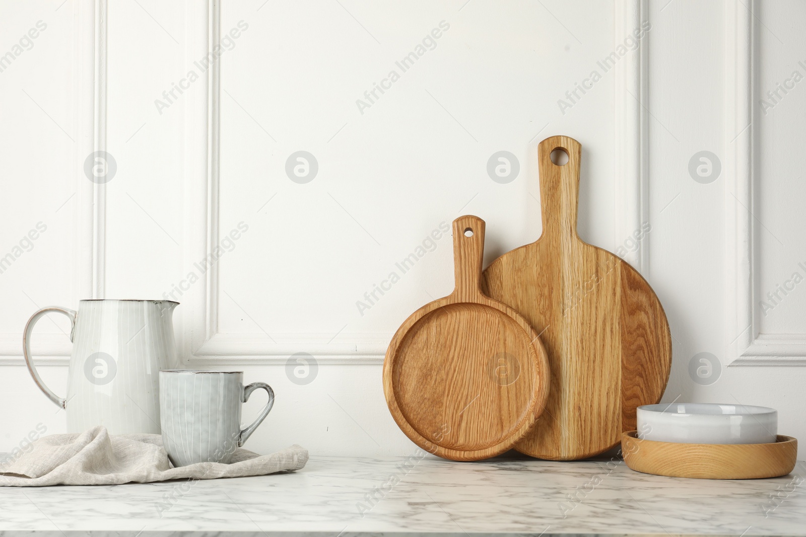Wooden cutting boards, dishware and towel on white marble table Photo of Wooden cutting boards, dishware and towel on white marble table