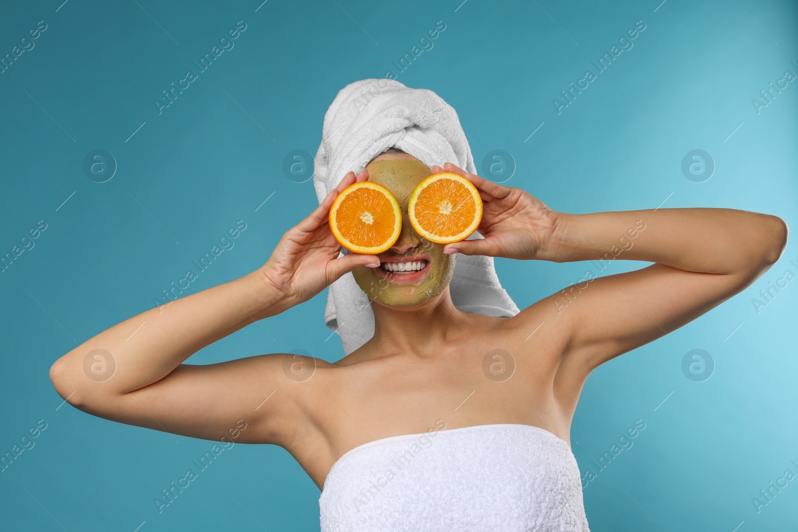 Photo of Beautiful woman with mask on face and cut orange against color background