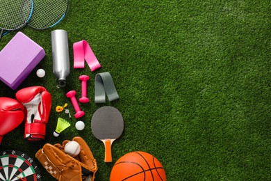 Photo of Different sport equipment on green grass, flat lay. Space for text