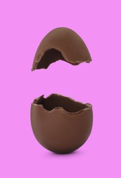 Image of Broken milk chocolate egg on fuchsia color background
