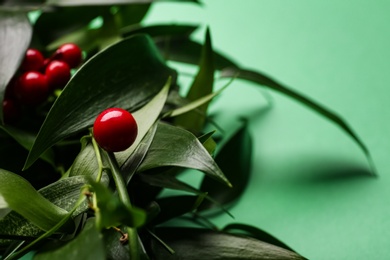 Photo of Beautiful handmade mistletoe wreath with red berries on green background, closeup. Traditional Christmas decor