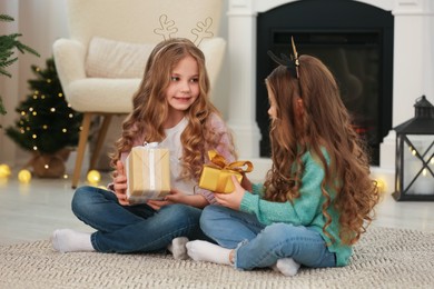 Photo of Cute little girls with Christmas gifts at home