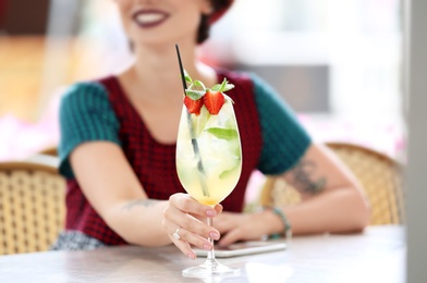 Photo of Young woman with glass of tasty lemonade in open-air cafe