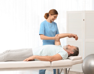 Photo of Physiotherapist working with patient in clinic. Rehabilitation therapy