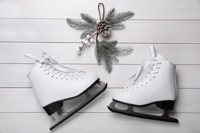 Photo of Pair of ice skates and Christmas decor on white wooden background, flat lay