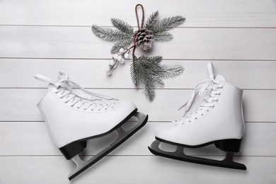 Pair of ice skates and Christmas decor on white wooden background, flat lay