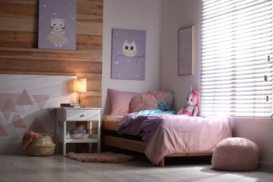 Photo of Bed with beautiful linens in children's room. Modern interior design