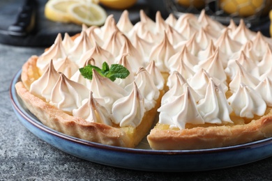 Photo of Cut delicious lemon meringue pie on grey table, closeup