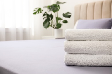 Photo of Stack of clean towels on bed indoors, closeup. Space for text