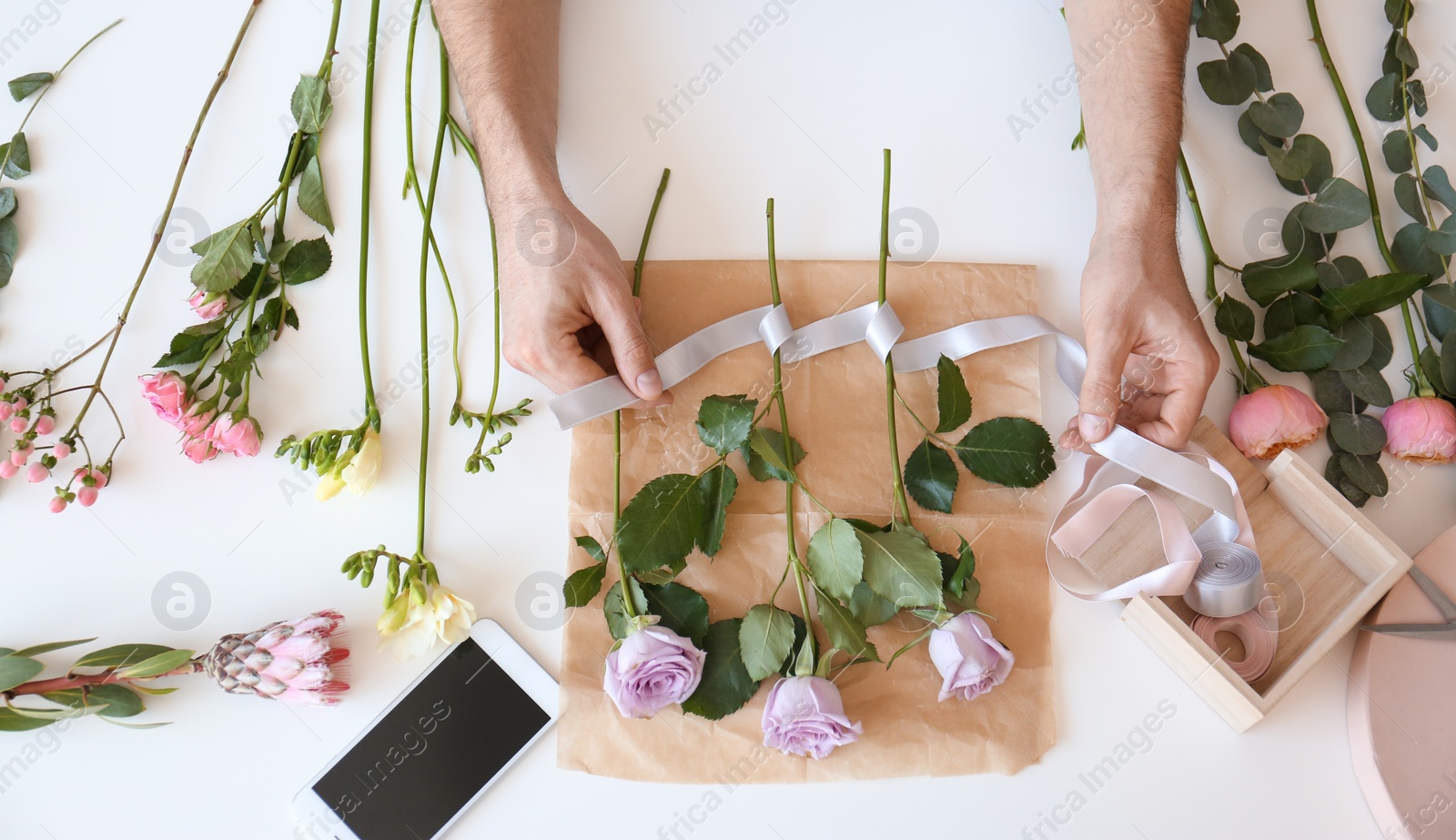 Photo of Male florist creating beautiful bouquet at table, top view