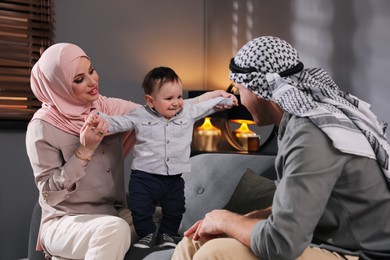 Photo of Happy Muslim family with little son in living room