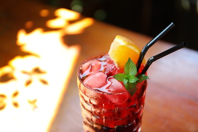 Photo of Glass of delicious cocktail with ice on table, closeup