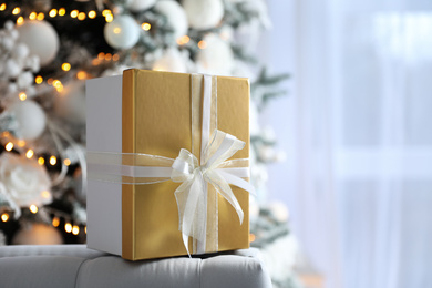 Photo of Christmas gift box on sofa in festive interior