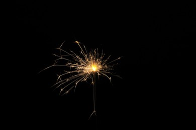 Photo of Burning sparkler stick on black background, space for text