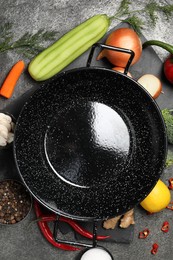 Photo of Empty iron wok and raw ingredients on grey table, flat lay