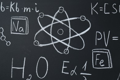 Photo of Different chemical formulas written with chalk on blackboard, closeup