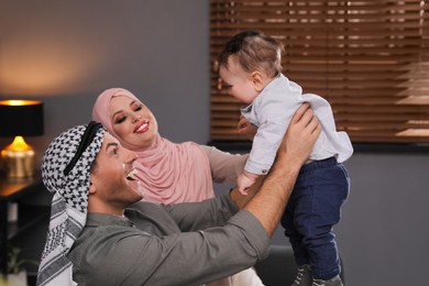Photo of Happy Muslim family with little son at home