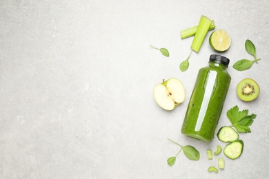 Green juice in bottle and fresh ingredients on light grey table, flat lay. Space for text