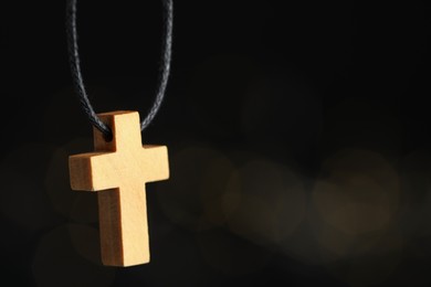 Photo of Christian cross on black background, closeup. Space copy text.