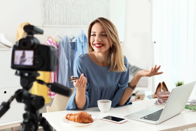Photo of Fashion blogger recording video on camera at home