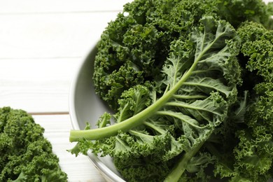 Photo of Fresh kale leaves on white table, closeup