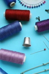 Photo of Thimble and different sewing tools on light blue background, above view