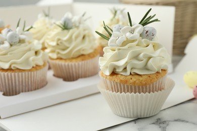 Photo of Tasty Easter cupcakes with vanilla cream on white marble table