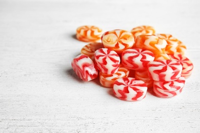 Photo of Pile of delicious colorful candies on wooden table. Space for text