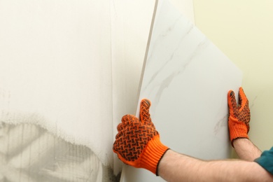 Photo of Man installing ceramic tile on wall, space for text. Building and renovation works