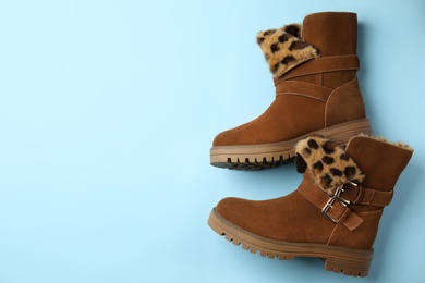 Photo of Stylish brown boots on light blue background, top view. Space for text