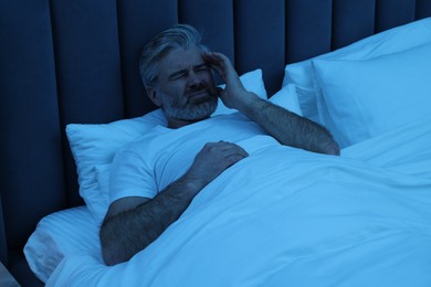 Photo of Mature man suffering from headache in bed at night
