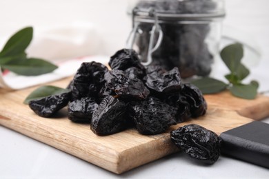 Photo of Tasty dried prunes on light table, closeup view