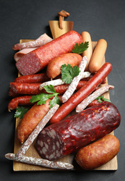 Photo of Different types of sausages served on black background, above view