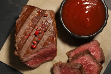 Photo of Delicious grilled beef steak with spices and tomato sauce on table, top view