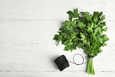 Photo of Bunch of fresh green parsley and twine on wooden background, flat lay. Space for text