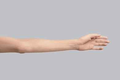 Photo of Young woman holding hand on grey background, closeup